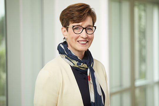 headshot of woman with short hair and glasses, smiling