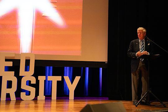 man talking into a microphone on stage
