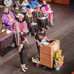 woman standing on a stage next to another woman at a podium
