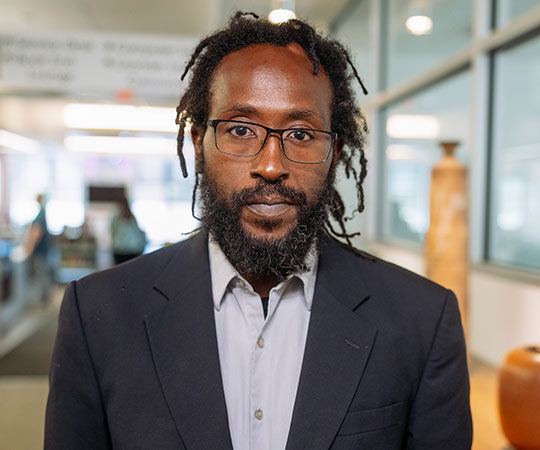 headshot of man in sport coat, wearing glasses
