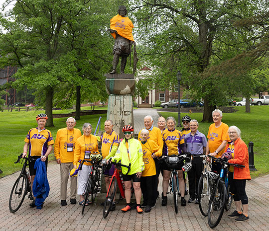 several people with bicycles standing in front of a statue