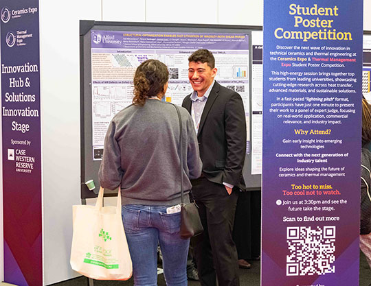 man standing in front of a poster talking to another person