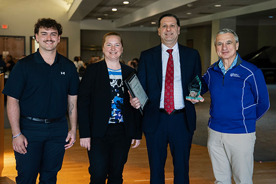 four people standing in a row, smiling