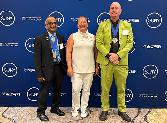 three people standing in a row, smiling