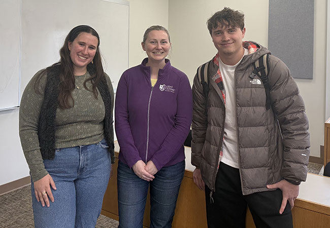 three people standing in a row, smiling