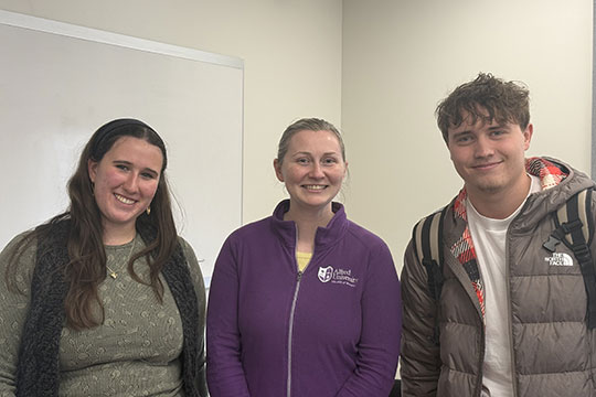 three people standing kin a row, smiling