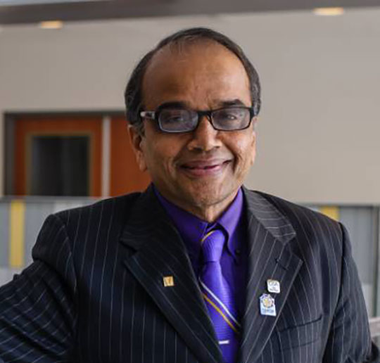 headshot of man in suit and tie, wearing glasses