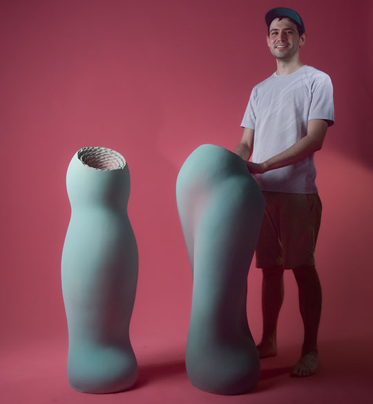 man standing next to two pieces of sculpture