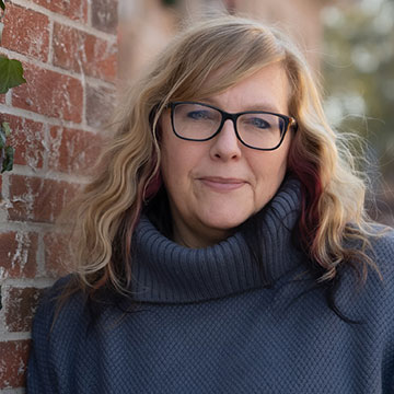 headshot of a woman with long hair and glasses
