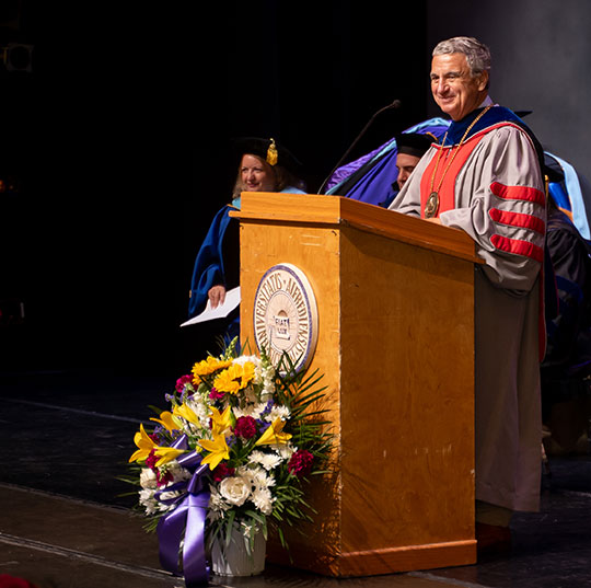 man in academic regalia at podium