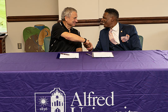 two people sitting at a table shaking hands