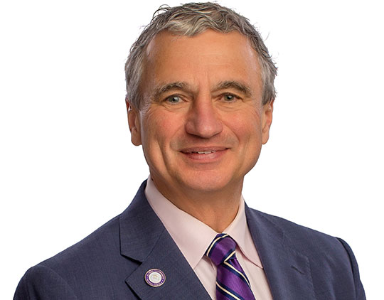 headshot of a man in a suit and tie, smiling