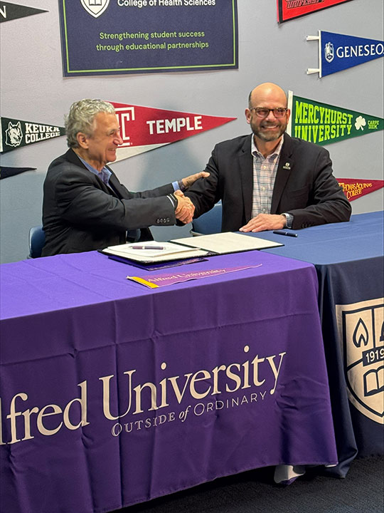 two people sitting at a table, shaking hands