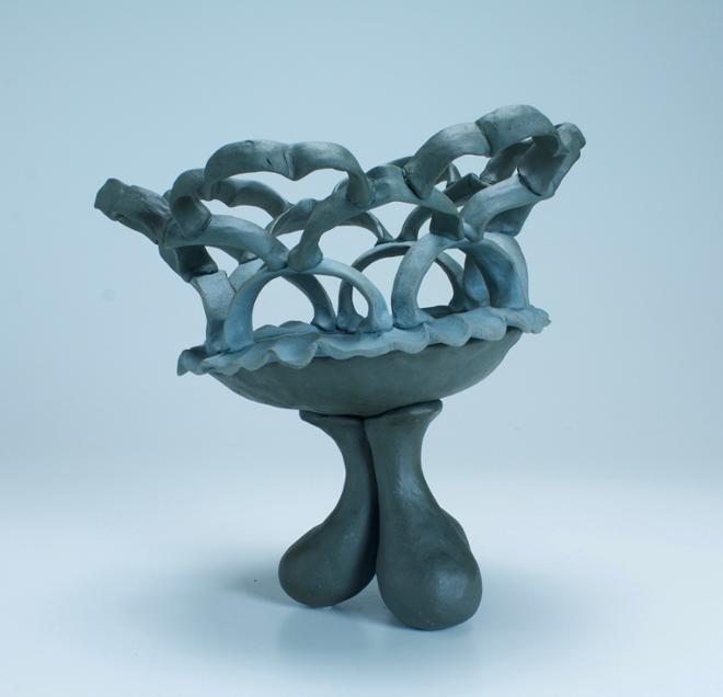 A smoky lattice of pinched handle-shaped structures connected in a loose geometrical pattern atop a shallow dish atop three drop-shaped legs.  