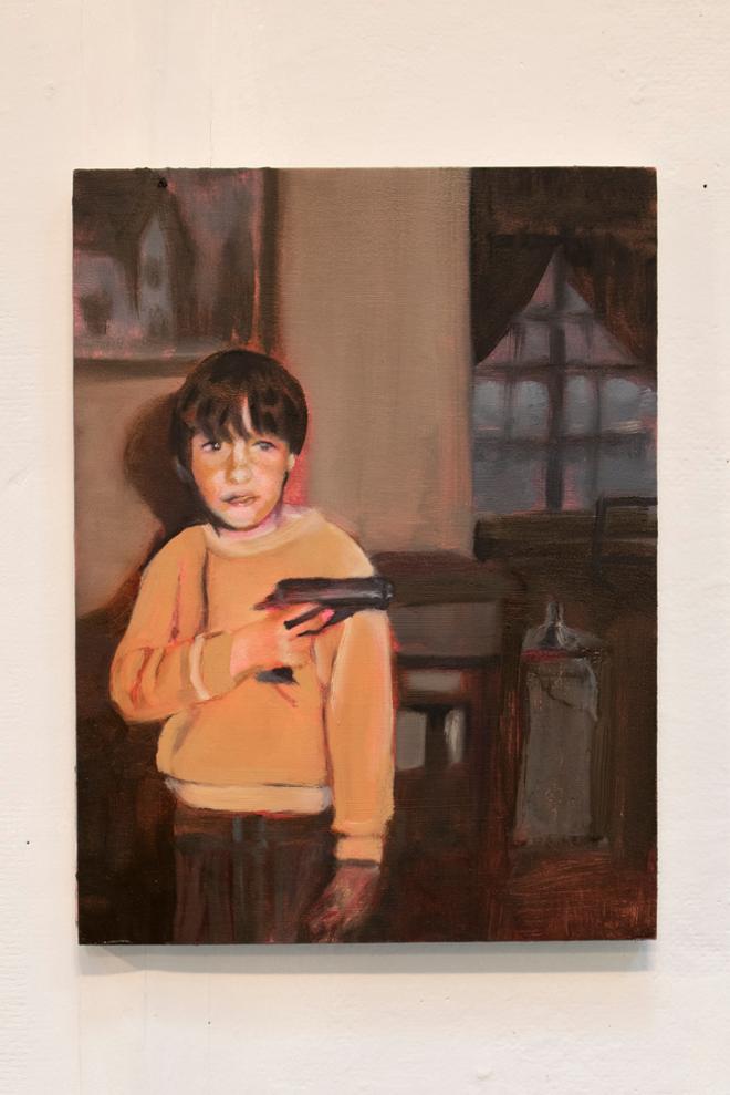 A little boy with a toy gun hiding behind a wall in a dark room. 
