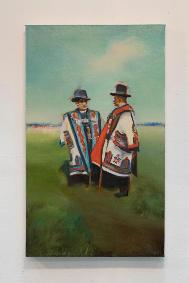 Two shepherds dressed in Hungarian folk costumes standing in a sunny field. 
