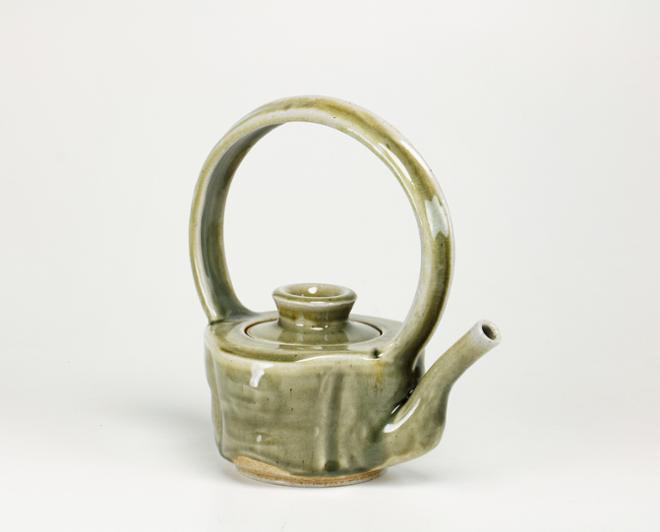  A large green celadon teapot with an exuberant overhead handle. 