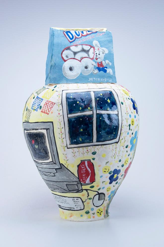 A large hand built vase with a blue bag of Bimbo donuts as the top. The illustrations on the vessel depict a woman surrounded by object such as a computer and window. 