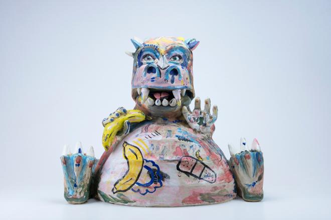 A ceramic dinosaur in a seated position holding a banana and smiling. He is glazed in many different colors. 