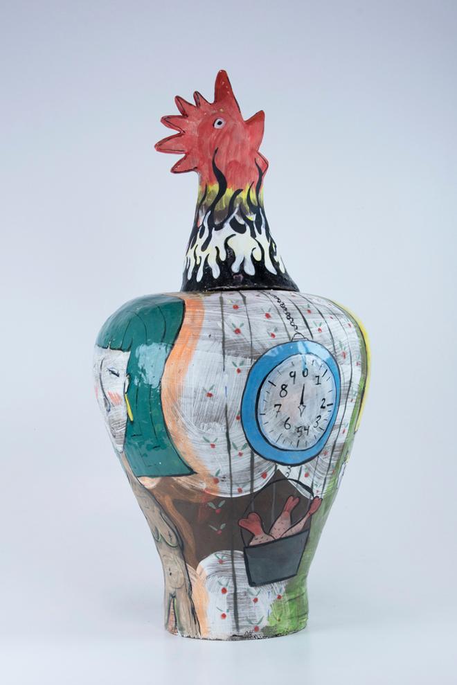 A terracotta vase with a chicken head as the top. The vase is decorated with a white slip and two female figures painted on either side. 