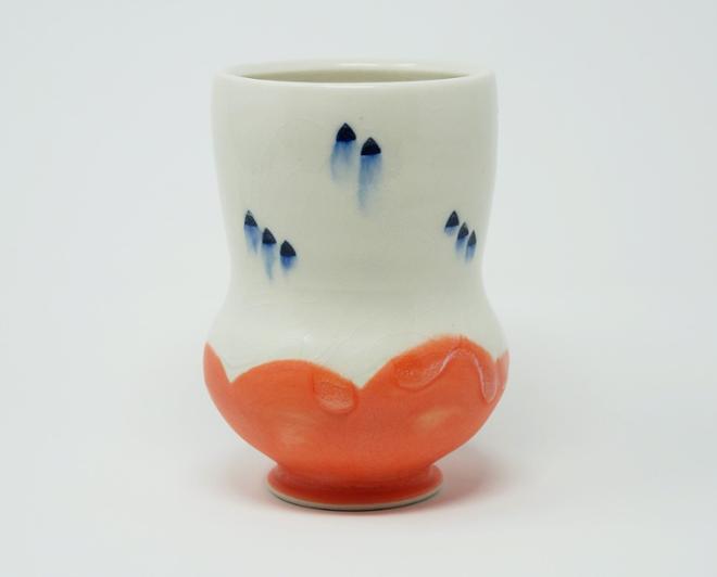 A white ceramic cup with blue dots and a salmon bottom. 