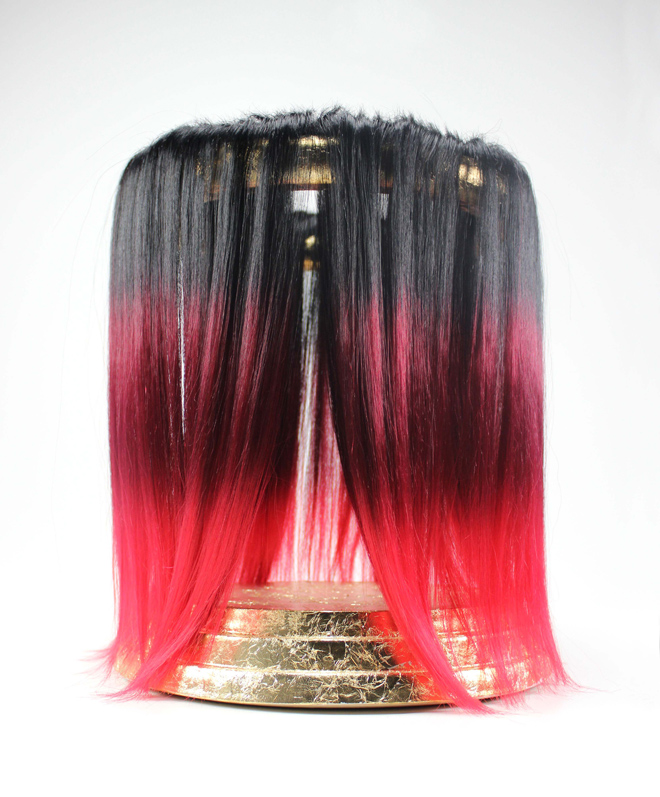 gold leaf circular stand with black and red hair draping over.