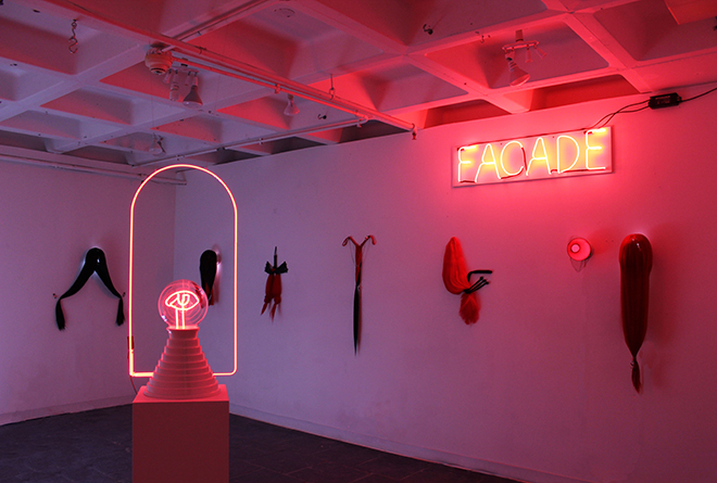 various hair pieces hanging on a wall with a red neon sign saying Facade.