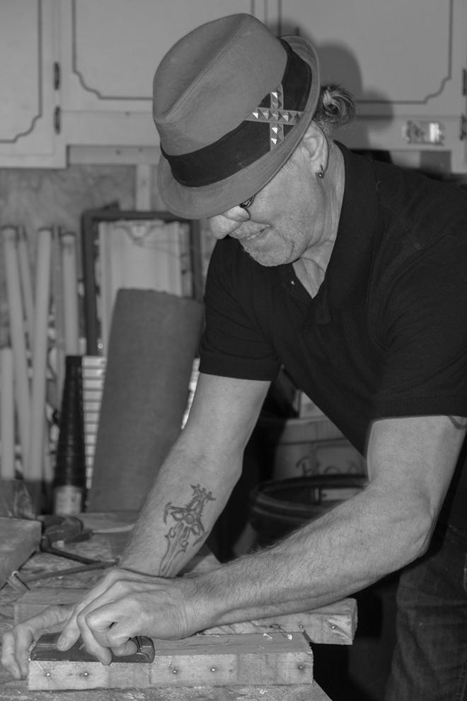 A photograph of a person sanding a block of wood from a side angle