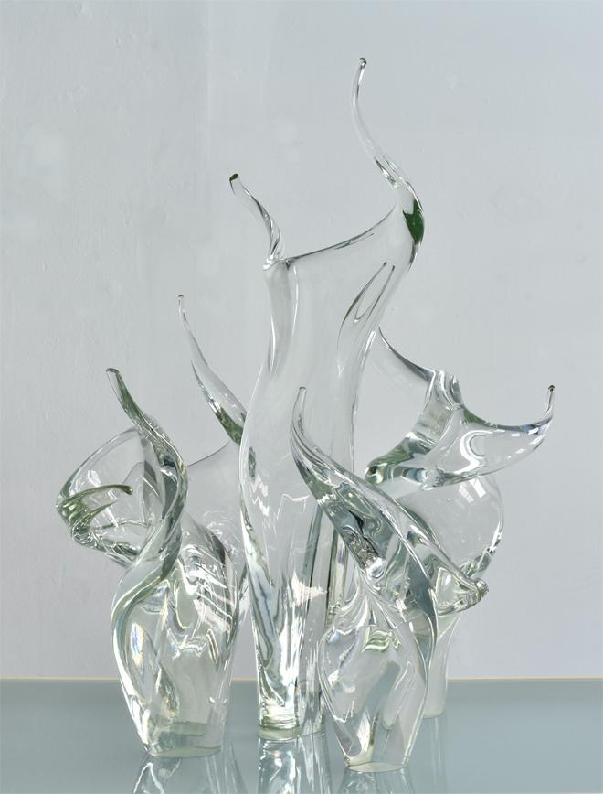 Five clear glass sculptures with the tallest one in the center. They bend and twist like dancers.