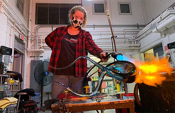 Bella in hot shop studio with blow torch, fire on glass object