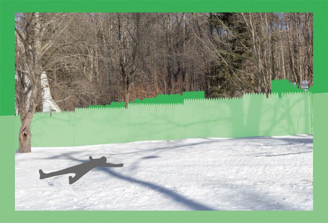 A horizontal photograph of a snowy yard with a forest in the background, and a light green fence running across the middle of the image dividing the two. The image is framed by a border of two different shades of light green with a dark gray figure laying in the snow making snow angels in the foreground.
