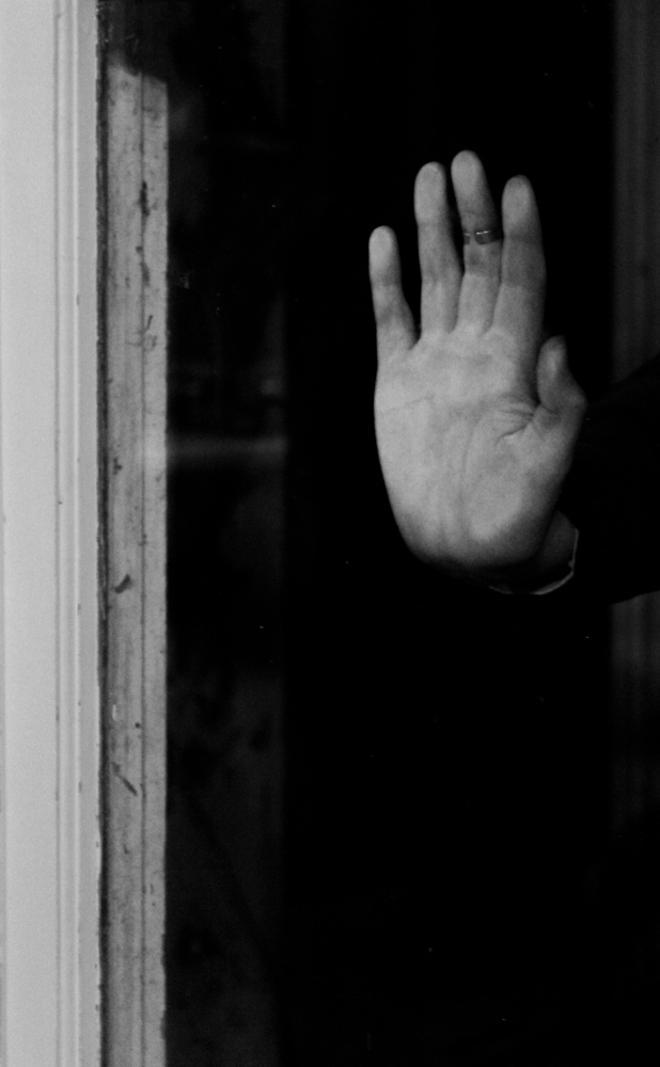 A hand on a window but the picture is taken in a way where you can't see where the hand is coming from.