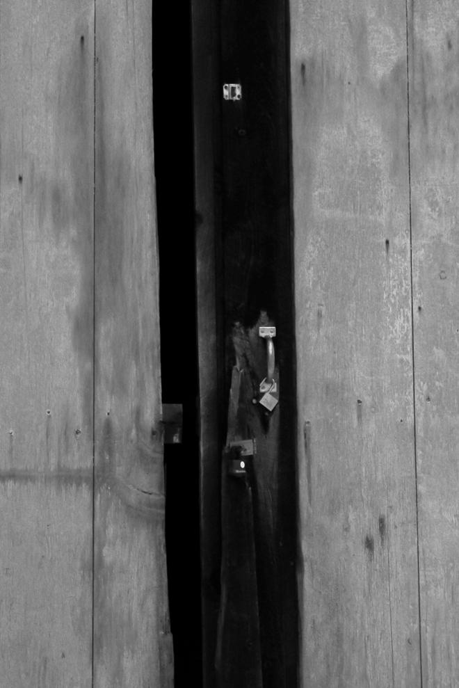 A barn door with an unlocked hook dangling off it