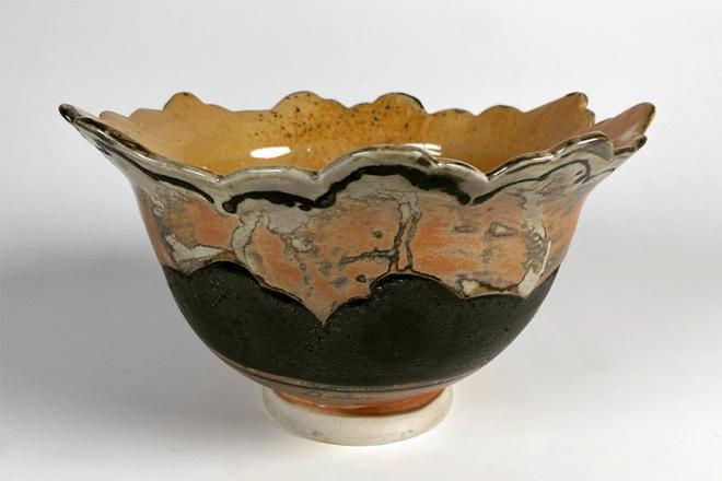 Ceramic bowl with an altered rim and finished with a baking soda glaze. This glaze flashed the surface making it orange. Black slip is used to contrast the light nature of the porcelain clay body. 