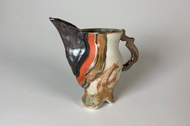 Ceramic pitcher with bird-like spout made with a combination of dark stoneware and porcelain and finished with a baking soda glaze that flashes the surface orange. Black and orange underglaze were also added to emphasize the form.