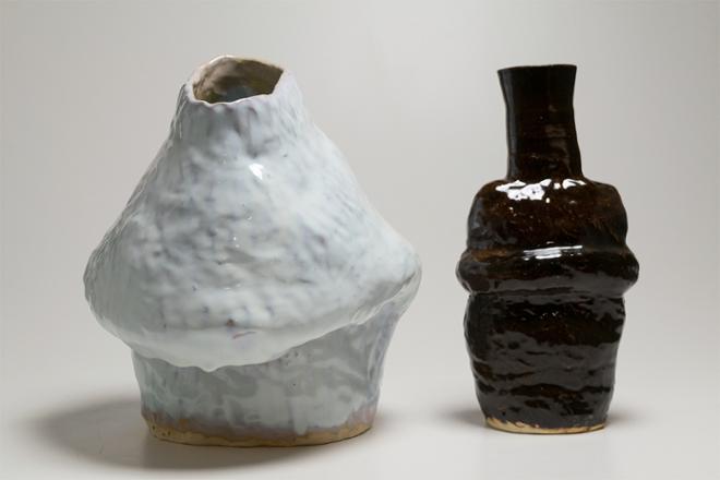 A vessel with an ovular top opening and a collapsed top portion vaguely resembling breast covered in a creamy blue white glaze.