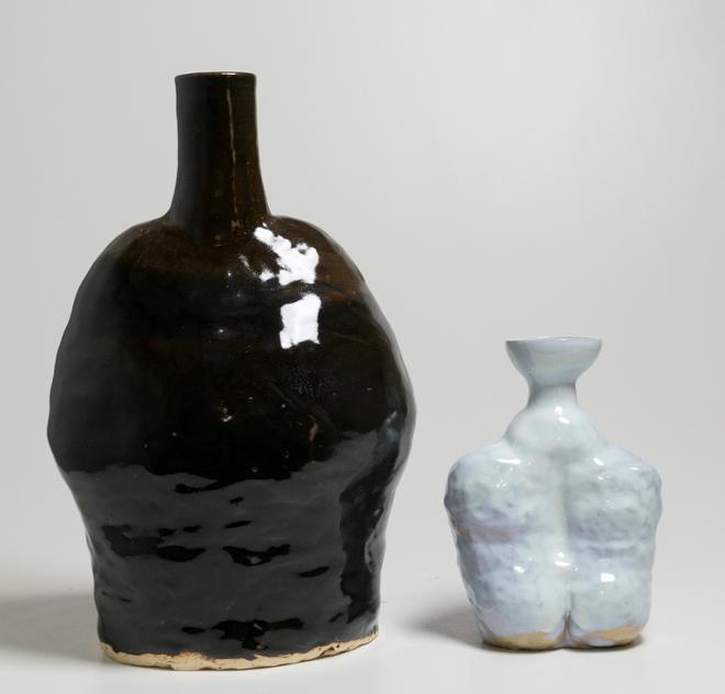 A large vase with a swell like the diaphragm opening and a long, tall neck that connects like a human neck covered in a dark brown black glaze.