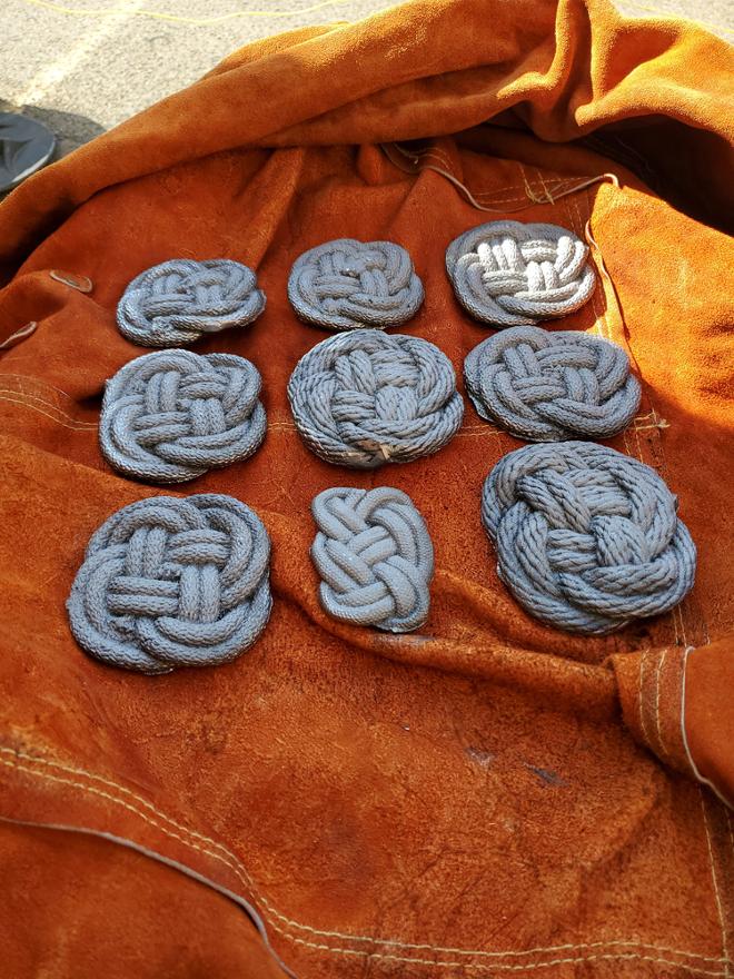 Eight Carrick bend knots, and one Celtic knot cast in Iron, laid on leather jacket. 
