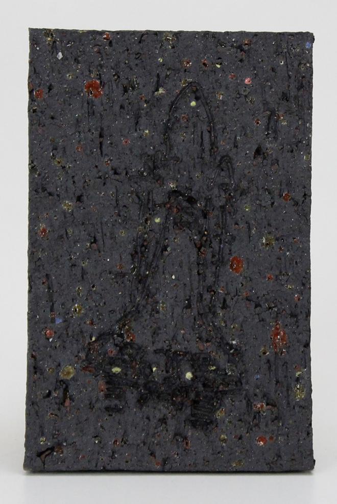 A black ceramic tile with flashes of color throughout. Etched into the surface is an image of a spaceship.