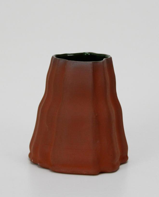 Red earthenware cup that tapers to the top. Green shiny glaze on the inside.