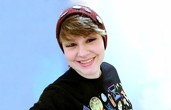 smiling Saymia wearing hat blue background