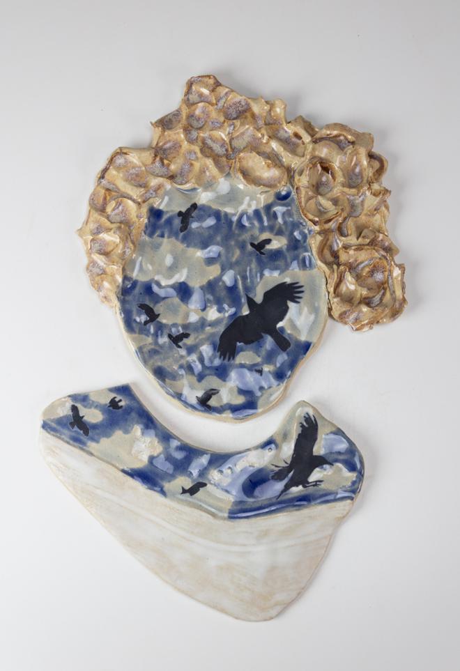 “Self Portrait”: A ceramic piece of the artist's head, instead of a face there are birds and a cloudy sky.