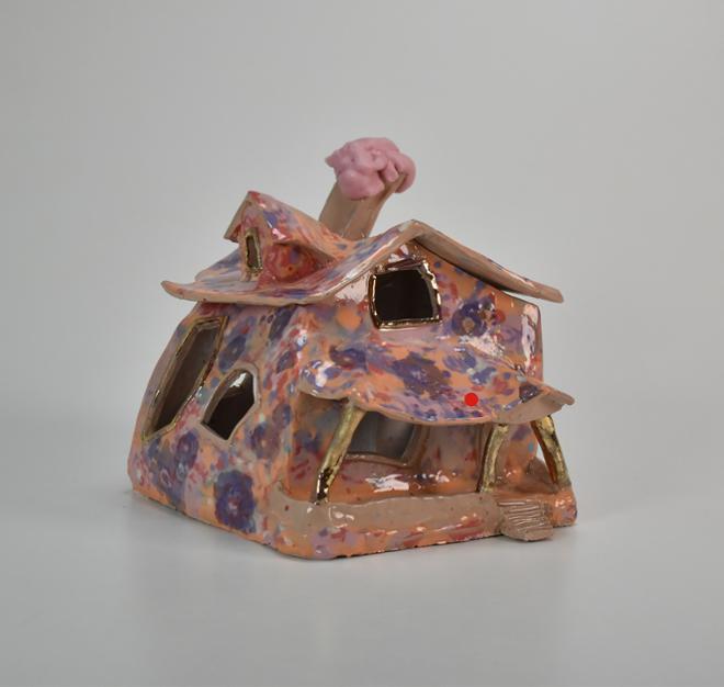 Distorted Orange ceramic house, covered in a multi colored floral pattern with floral decals with gold luster accents.