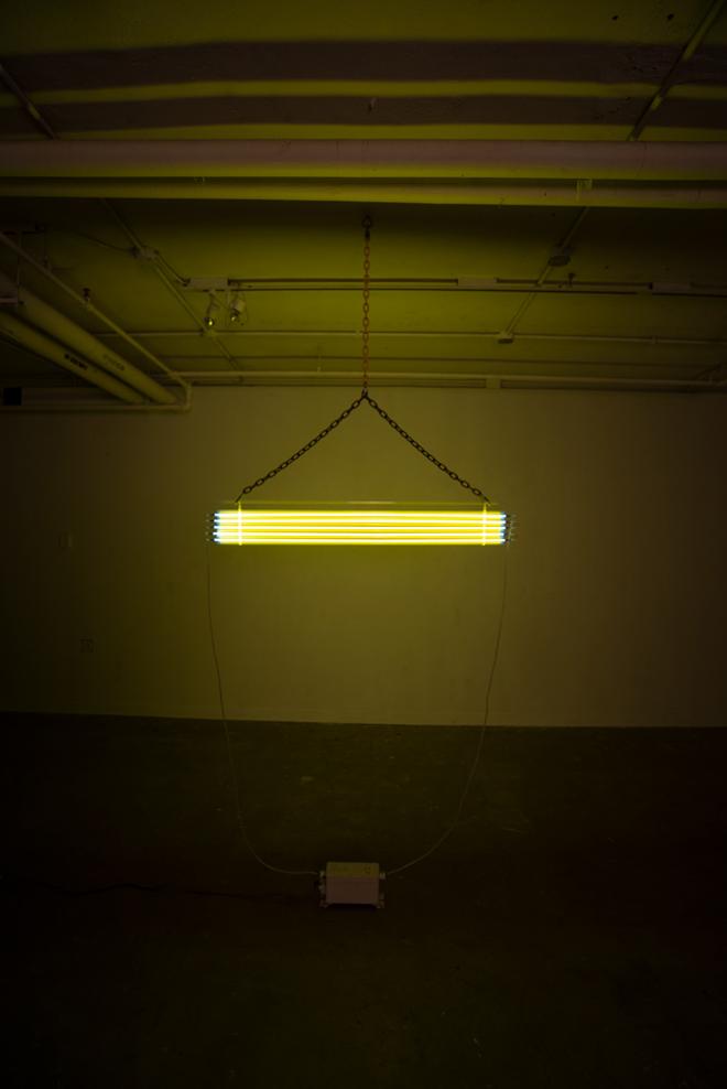 Five yellow tubes suspended from the ceiling using chain and custom 3d printed parts.  The yellow light is filling the entire room.  