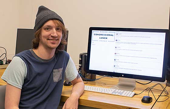 Sam Schultheis posing with computer and work. 