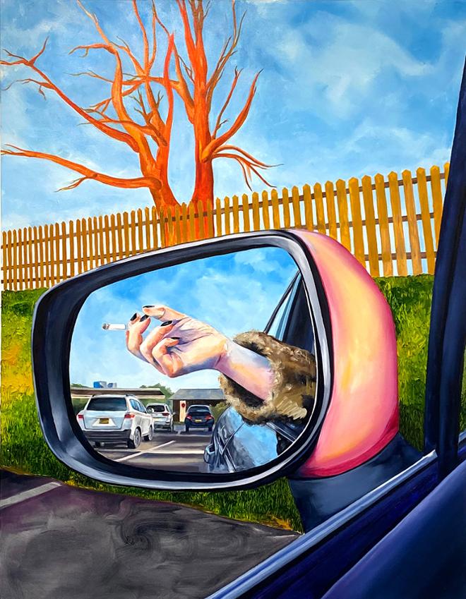 A hand is resting on the windowsill of a car, holding a cigarette. This is reflected in the side mirror of that car. Inside the side mirror, we see a parking lot with three cars, a blue sky, and office buildings. Looking past the side mirror, we see a brown fence, orange bare tree, and green grass.