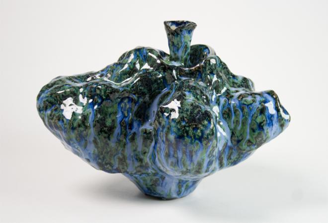A small, stout yet delicate ceramic vessel is displayed reaching out in its breadth but sits carefully on its narrow bottom, glazed with a dark rippling blue and green rutile that mimics waterfalls over a mossy gorge.