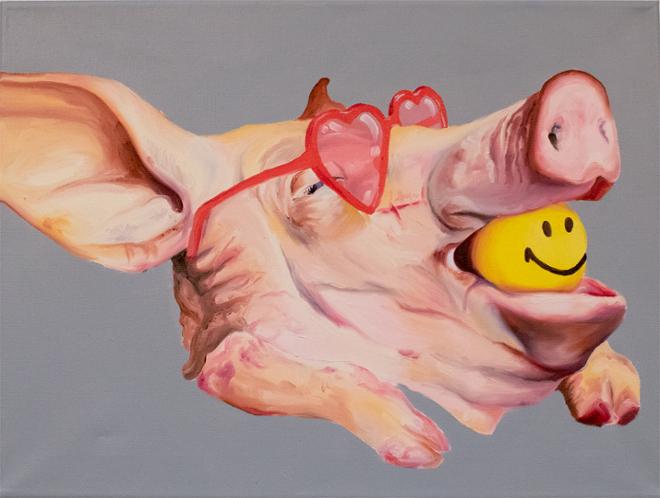 A severed pig head wears rose-tinted heart sunglasses and has a smiley face ball in its mouth.