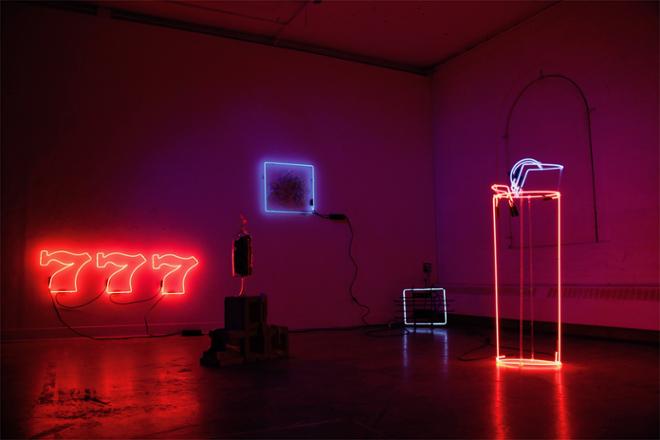 An installation using the corner of a gallery. This installation consists of a neon sign spelling out, “777” a neon lighter, a neon framed glass sculpture made from slumped beer bottles and a repurposed neon sign.