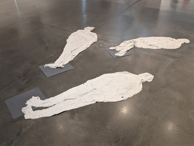 Three paper silhouettes lying on the floor. 